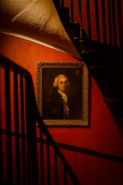 Antique painting on a red wall in the main stairway at The App AvaiBook Scotland